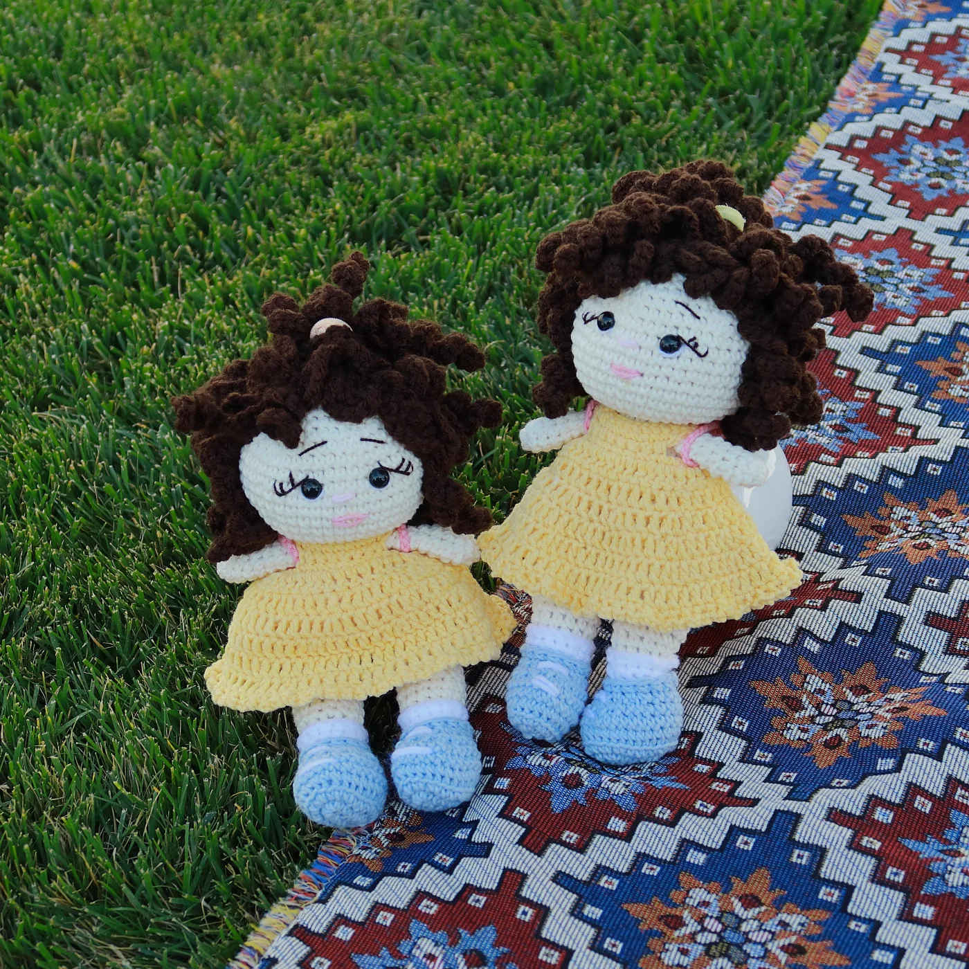 Two handmade Lori dolls on grass and an Armenian rug